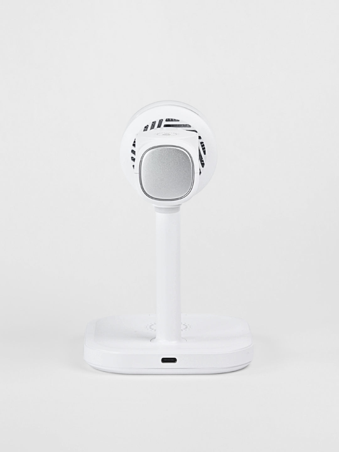 Rear view of the white Schlüssel 3-in-1 wireless charging station, showcasing the USB-C power input port at the base and a silver metallic module on the back against a light gray background.