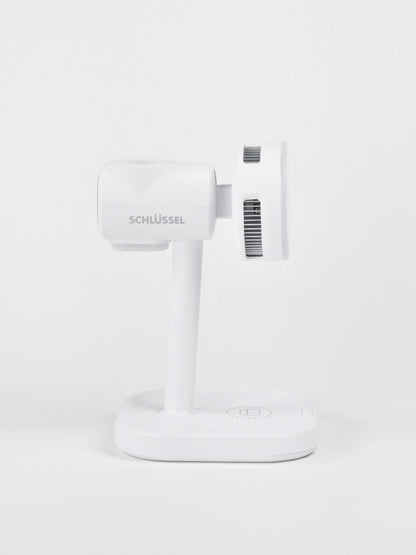 Side profile view of the white Schlüssel 3-in-1 wireless charging station, highlighting the brand logo, cooling ventilation vents, and flat charging base against a seamless gray background