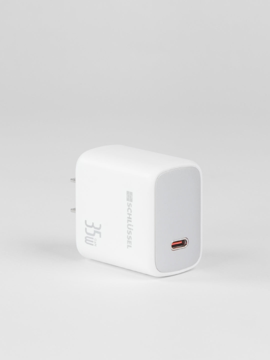 A standalone white Schlüssel 35W GaN wall charger block with a silver front faceplate and a single USB-C port, captured from a three-quarter perspective on a light gray background