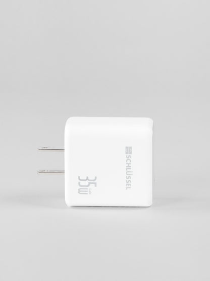 Side profile view of a white Schlüssel 35W GaN wall charger block with two flat metal AC power prongs on the left, shot against a solid light gray background
