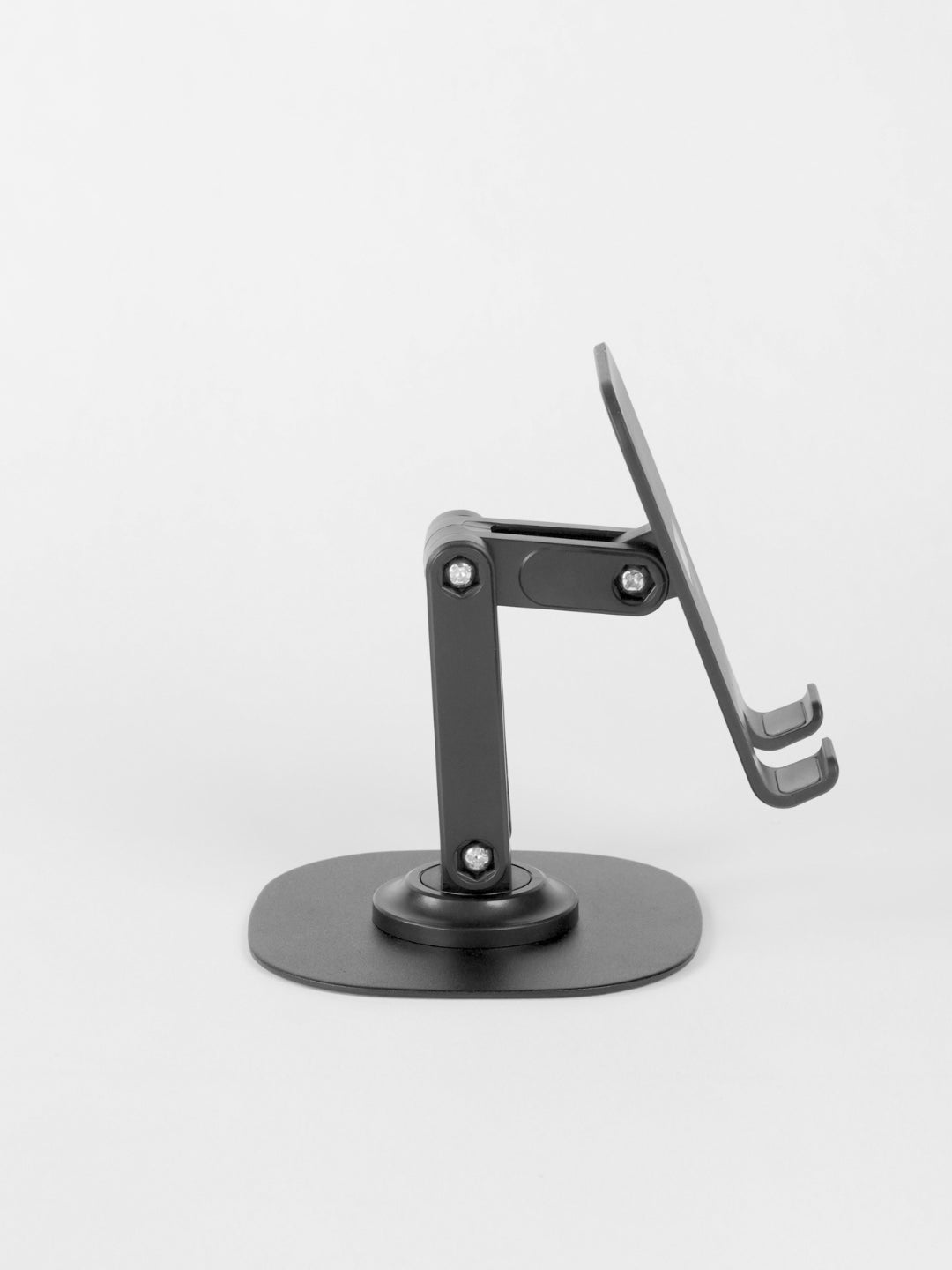 Side view of the black Schlüssel adjustable desktop phone stand, highlighting its multi-joint articulated arm mechanism and flat weighted base against a light gray background