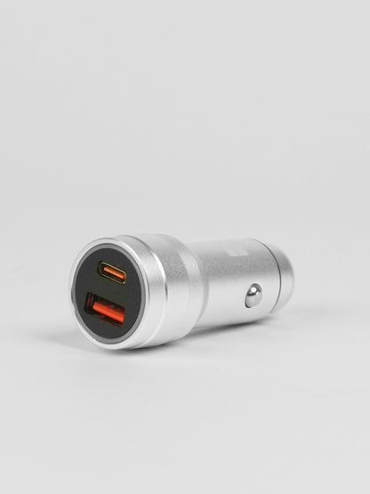 Schlussel brand metal car charger featuring dual fast-charging ports (one USB-C and one USB-A) with vibrant orange interiors, set against a seamless light gray background