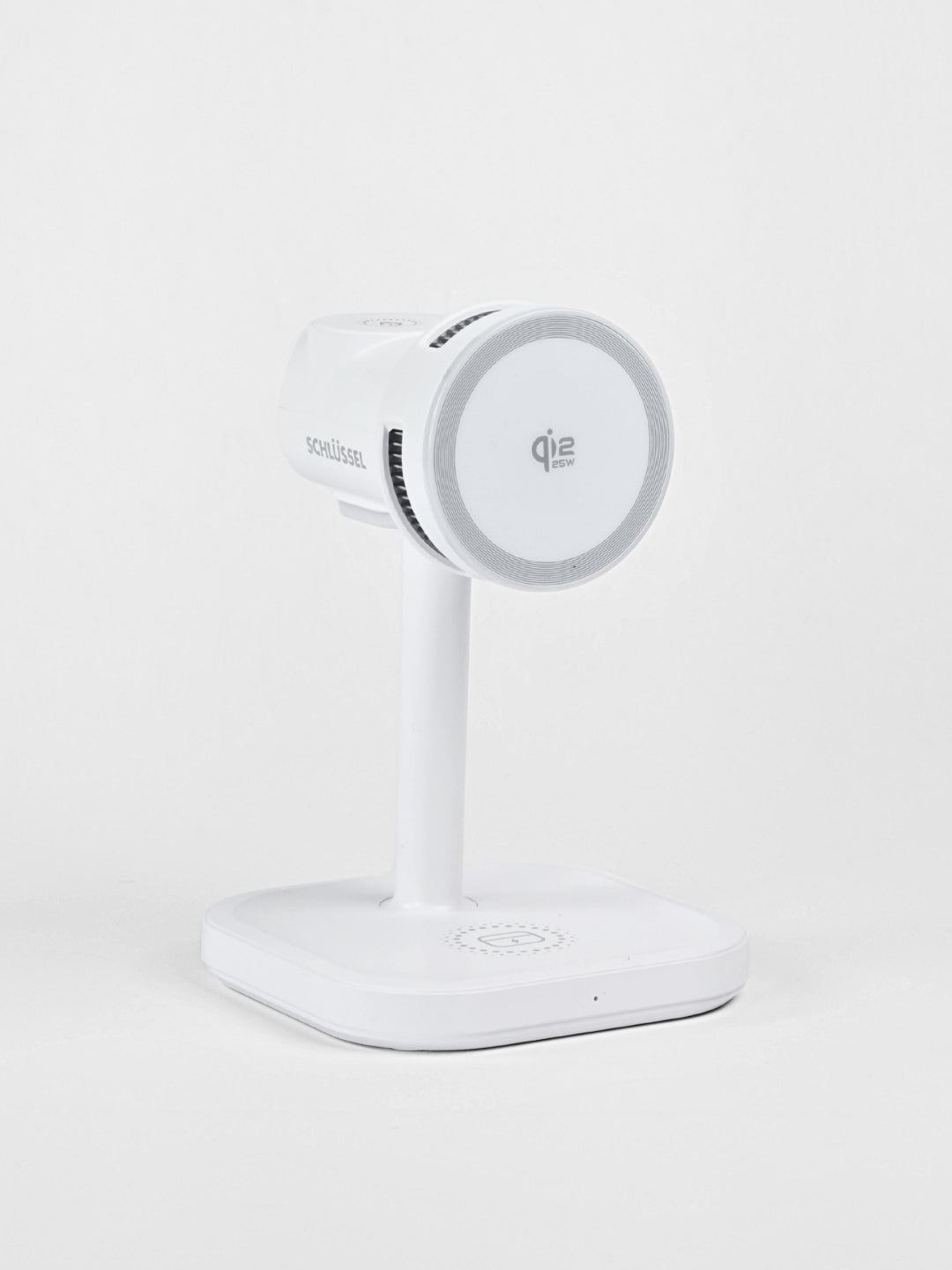 A standalone white Schlüssel 3-in-1 wireless charging station featuring a Qi2 15W magnetic phone mount, captured from a three-quarter angle against a neutral gray background